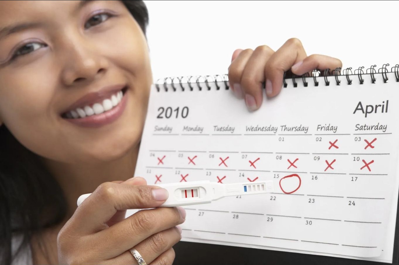 Frau zeigt Entbindungstermin auf dem Kalender