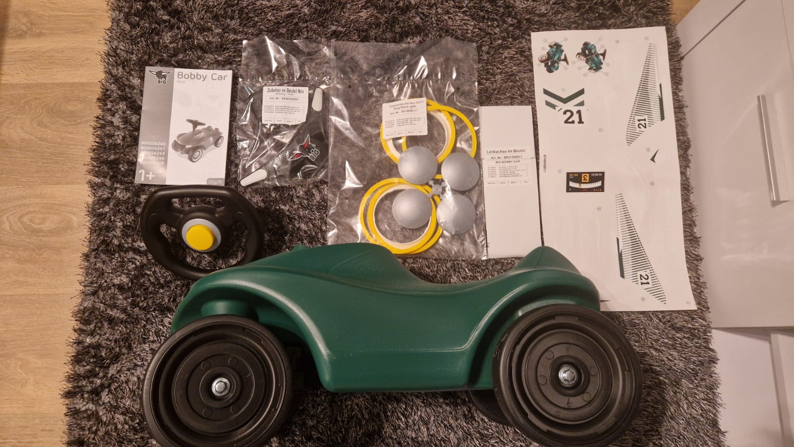 Einzelteile des BIG Bobby Car Neo RS Grün vor dem Aufbau