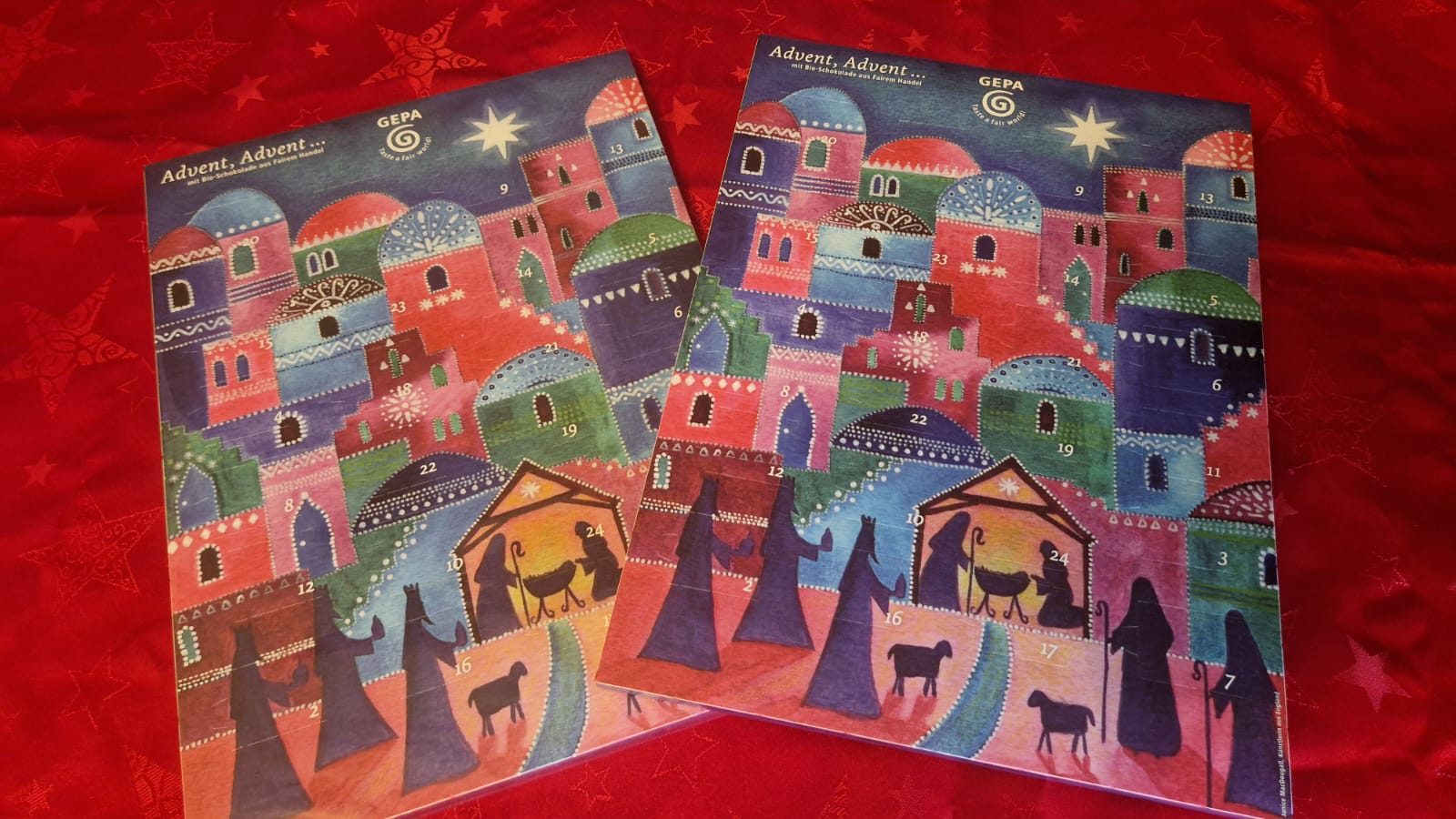 Zwei ungeöffnete GEPA Adventskalender auf rotem Weihnachtshintergrund
