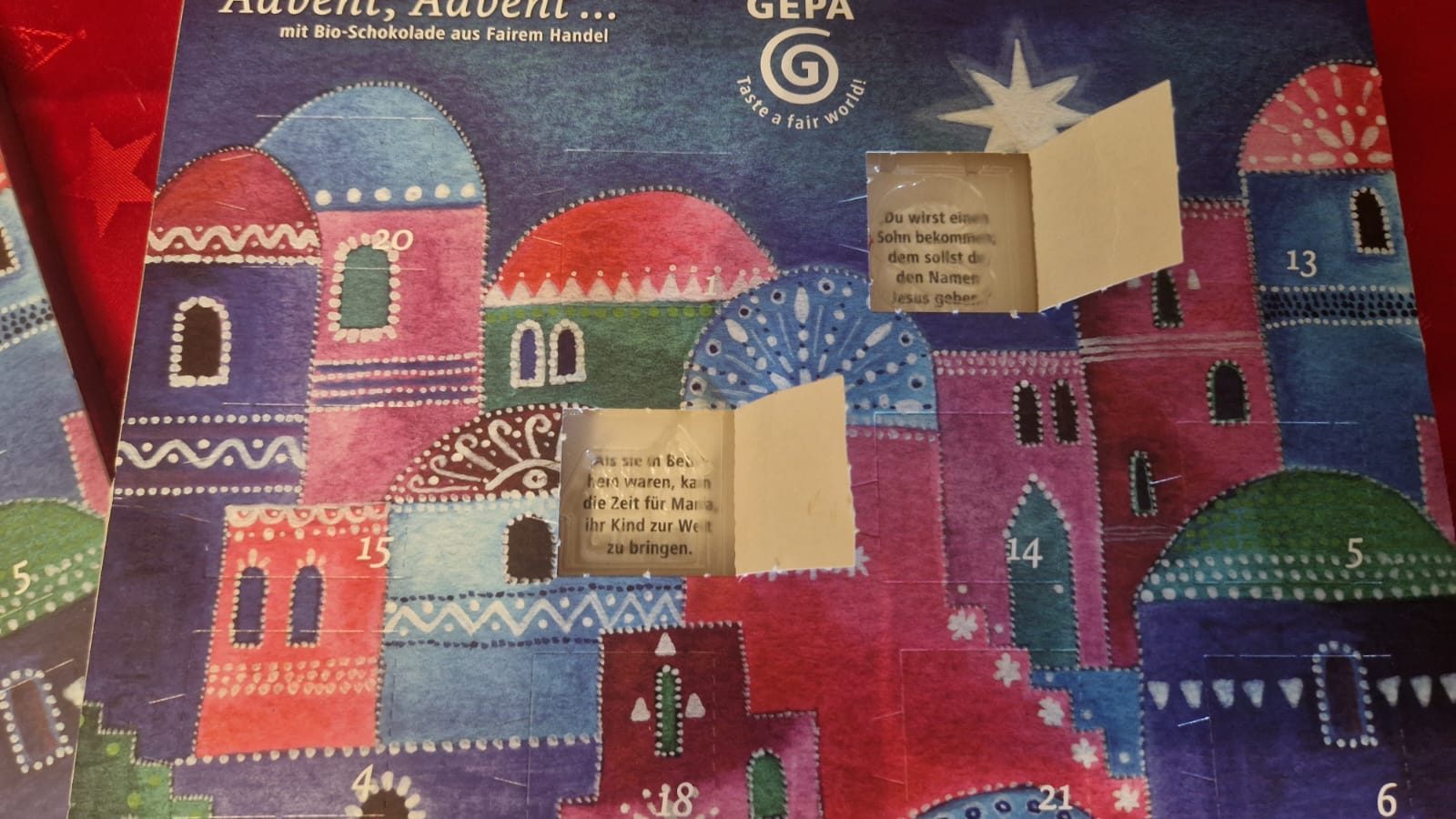 Geöffnete Türchen des GEPA Adventskalenders mit Abschnitten der Weihnachtsgeschichte