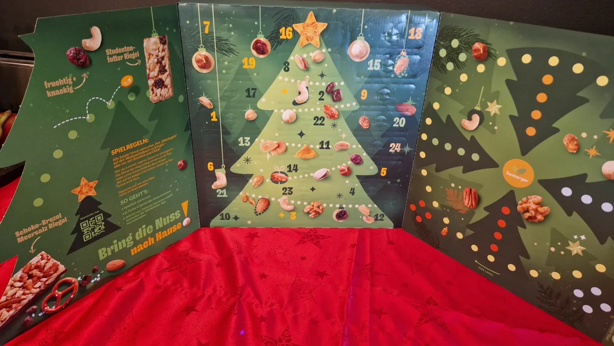 Aufgeklappter Seeberger Adventskalender 2026 mit 24 Türchen und dem Spiel Bring die Nuss nach Hause